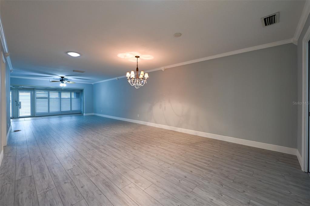 350 Boca Ciega Point Boulevard St. Petersburg, FL 33708 - Photo 6 of 32 an empty room with wooden floor chandelier and windows
