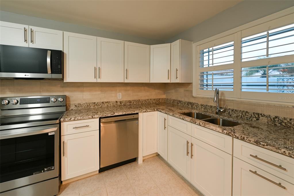 350 Boca Ciega Point Boulevard St. Petersburg, FL 33708 - Photo 10 of 25 a kitchen with granite countertop white cabinets and a stove