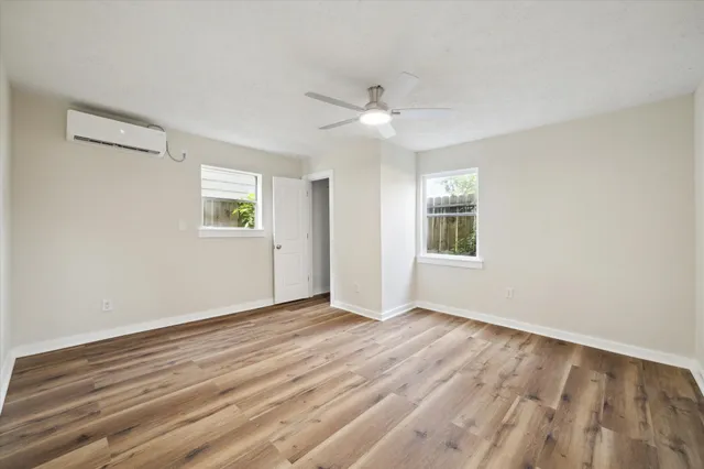 a view of empty room with wooden floor and fan
