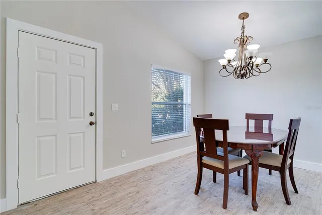 a dining room with wooden floor a chandelier a wooden table and chairs