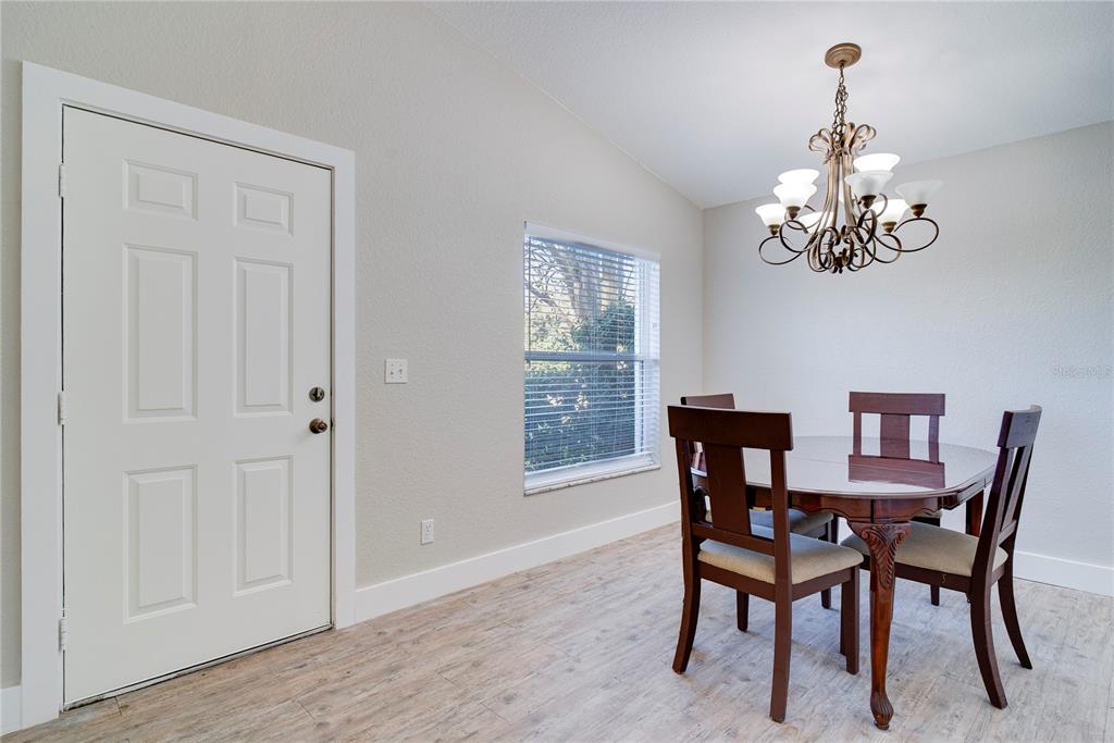 108 Brittany Road Mascotte, FL 34753 - Photo 2 of 23 a dining room with wooden floor a chandelier a wooden table and chairs