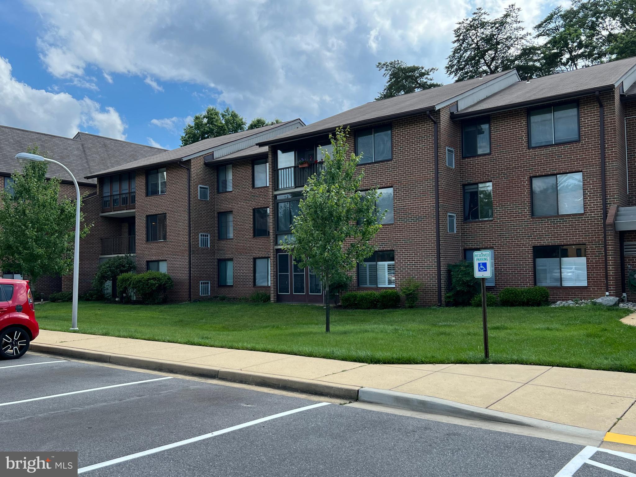 a view of a brick house with a yard and large trees