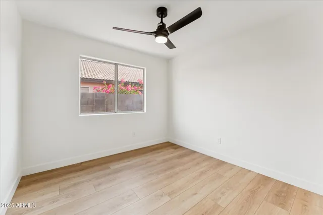 an empty room with wooden floor and ceiling fan