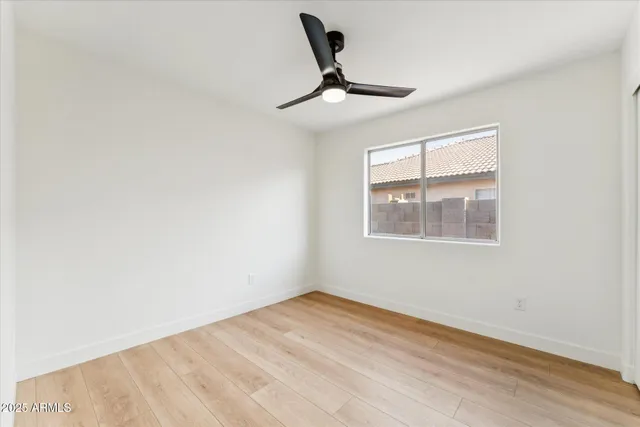 a view of empty room with wooden floor and fan
