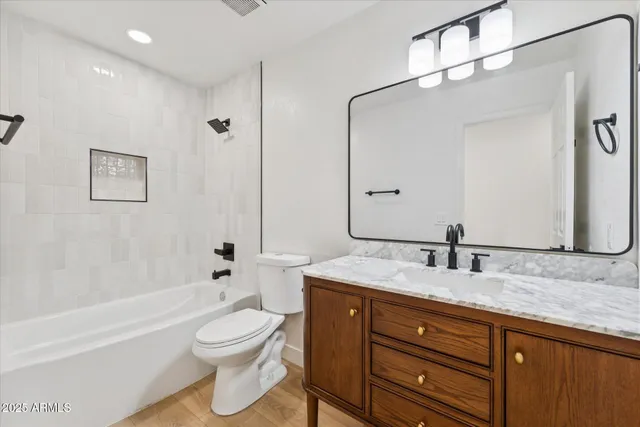 a bathroom with a granite countertop sink toilet a large mirror a bathtub and shower