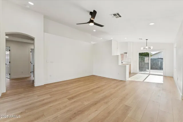 a view of empty room with wooden floor and ceiling fan