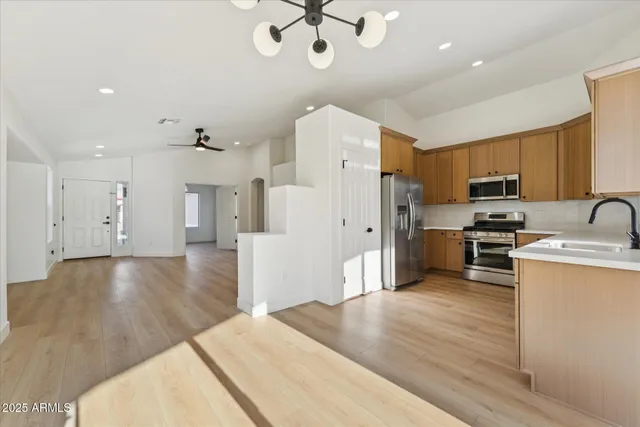 a kitchen with stainless steel appliances granite countertop a refrigerator a stove oven a sink dishwasher and white cabinets with wooden floor