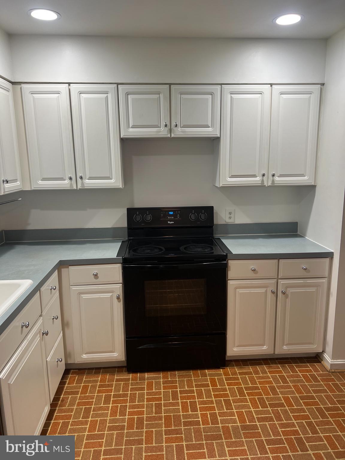 2040 Golf Course Drive Reston, VA 20191 - Photo 8 of 34 a kitchen with white cabinets and black appliances