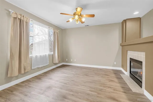 a view of an empty room with a window and a kitchen