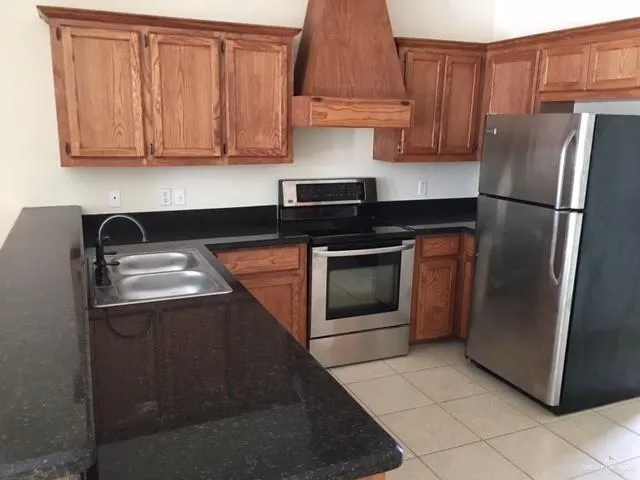 a kitchen with granite countertop a refrigerator stove and cabinets