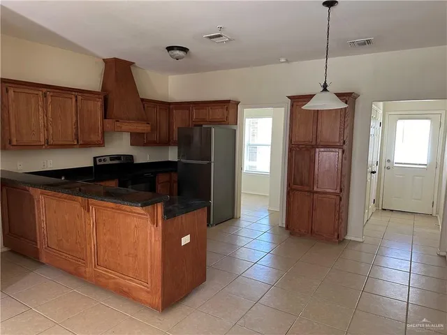 a kitchen with stainless steel appliances granite countertop a refrigerator a stove and a sink with wooden cabinets