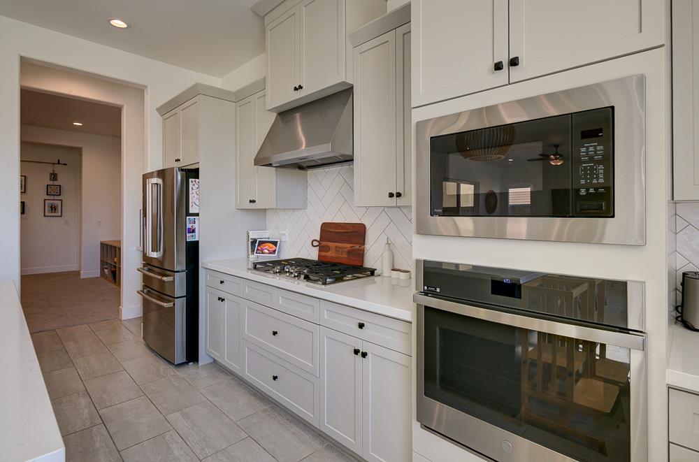 1048 Beaver Pond Loop Madera, CA 93636 - Photo 16 of 27 a kitchen with stainless steel appliances granite countertop a stove a microwave and refrigerator