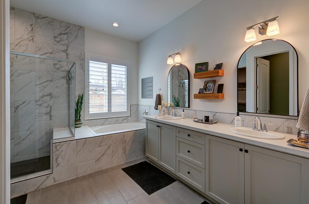 1048 Beaver Pond Loop Madera, CA 93636 - Photo 17 of 27 a spacious bathroom with a double vanity sink mirror and bathtub