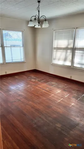 an empty room with wooden floor cabinet and windows