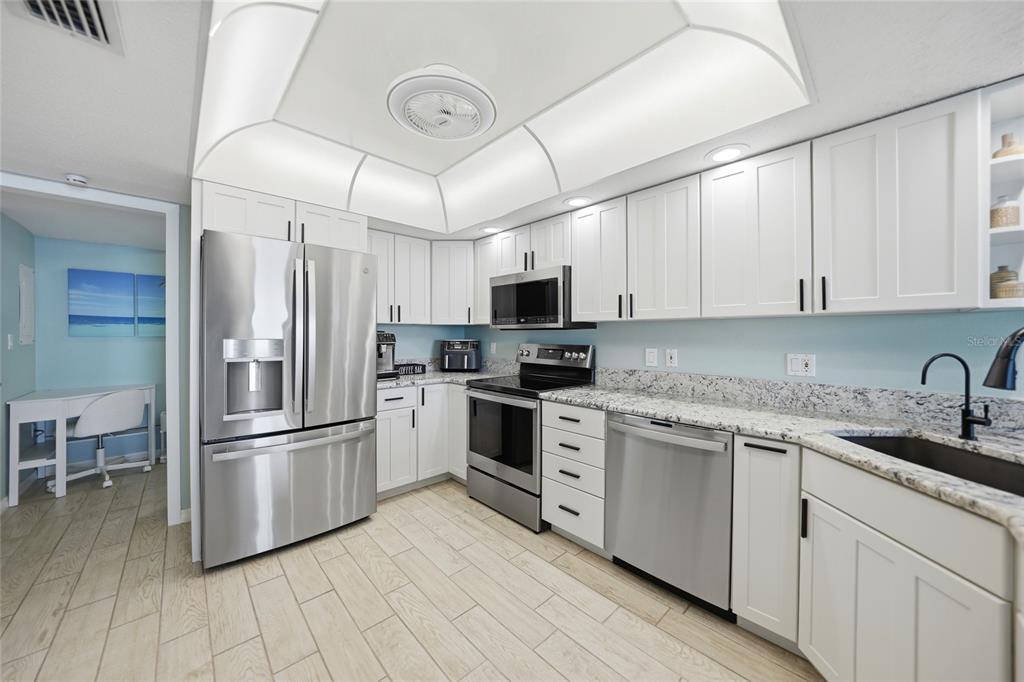 1 Colony Point Drive, Unit A10 Punta Gorda, FL 33950 - Photo 10 of 31 a kitchen with stainless steel appliances granite countertop a refrigerator a stove a sink and white cabinets with wooden floor