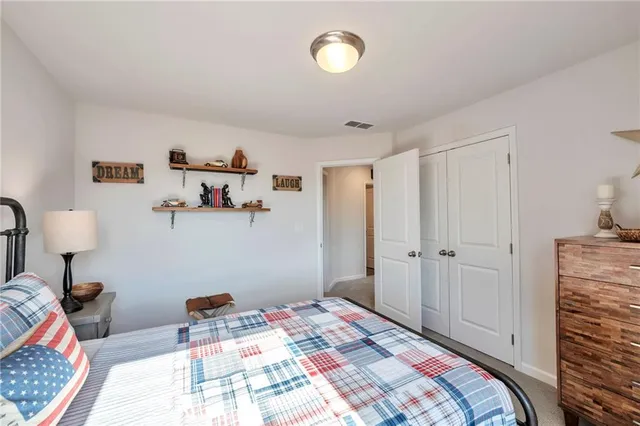 a bedroom with a bed and a lamp on the dresser