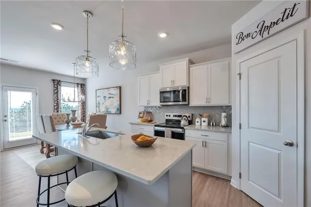 a open dining room with stainless steel appliances kitchen island granite countertop a table chairs and a refrigerator