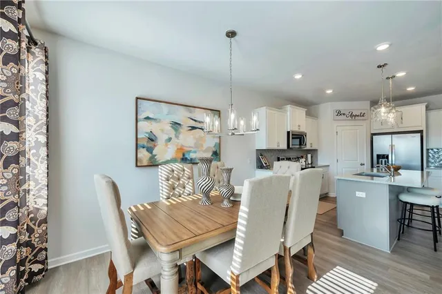 a view of a dining room with furniture a kitchen and chandelier
