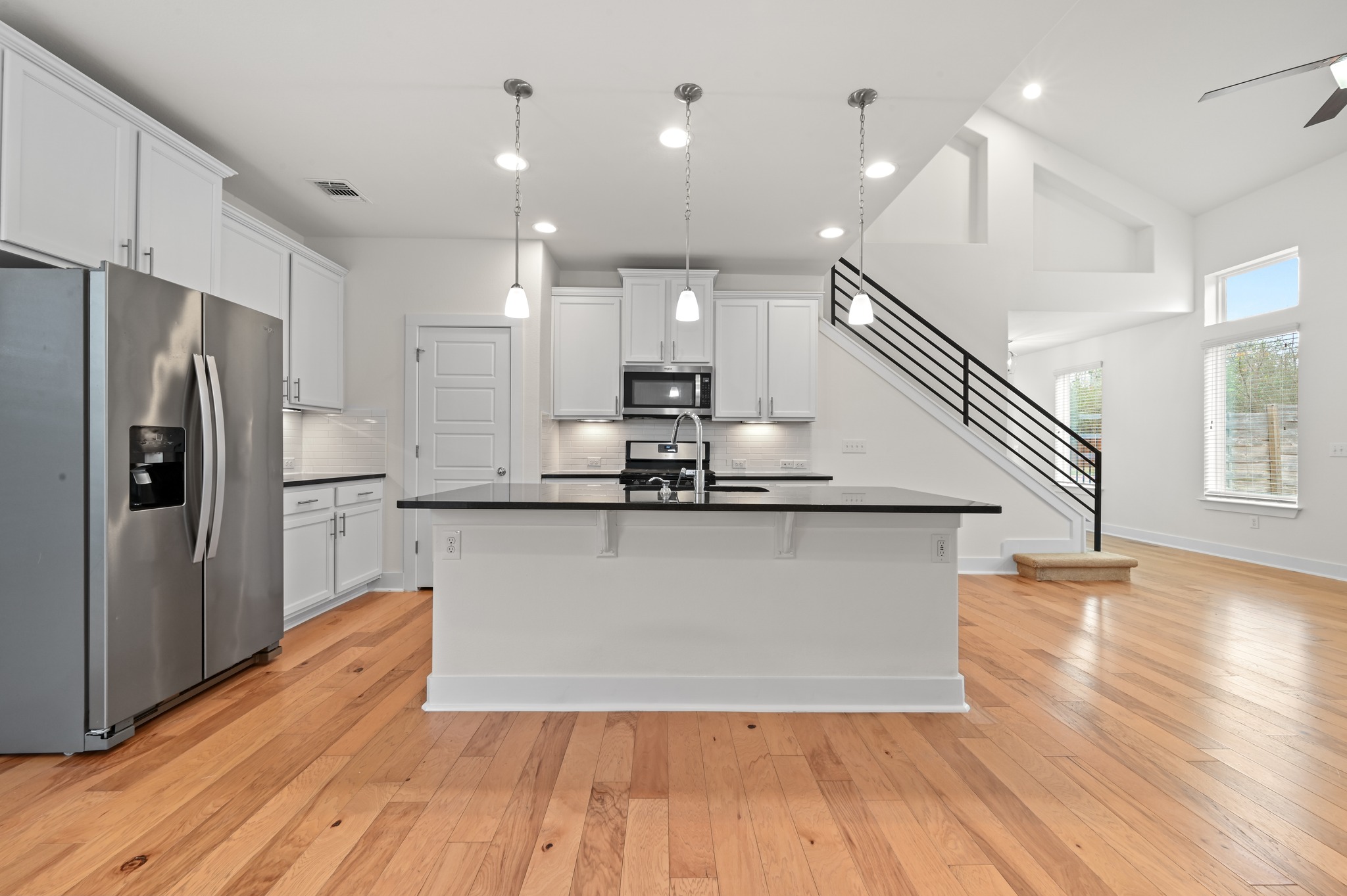 2204 Theseus Pass Austin, TX 78741 - Photo 12 of 31 a kitchen with kitchen island a refrigerator wooden floor and a counter top space