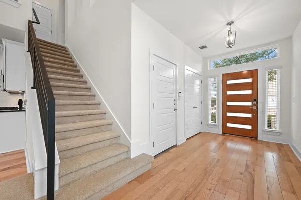 a view of an empty room with wooden floor and stairs