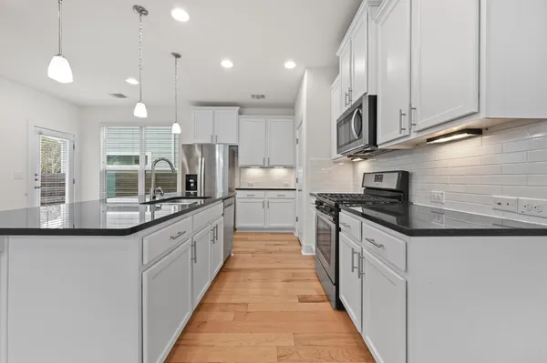 a kitchen with stainless steel appliances granite countertop a sink refrigerator and microwave