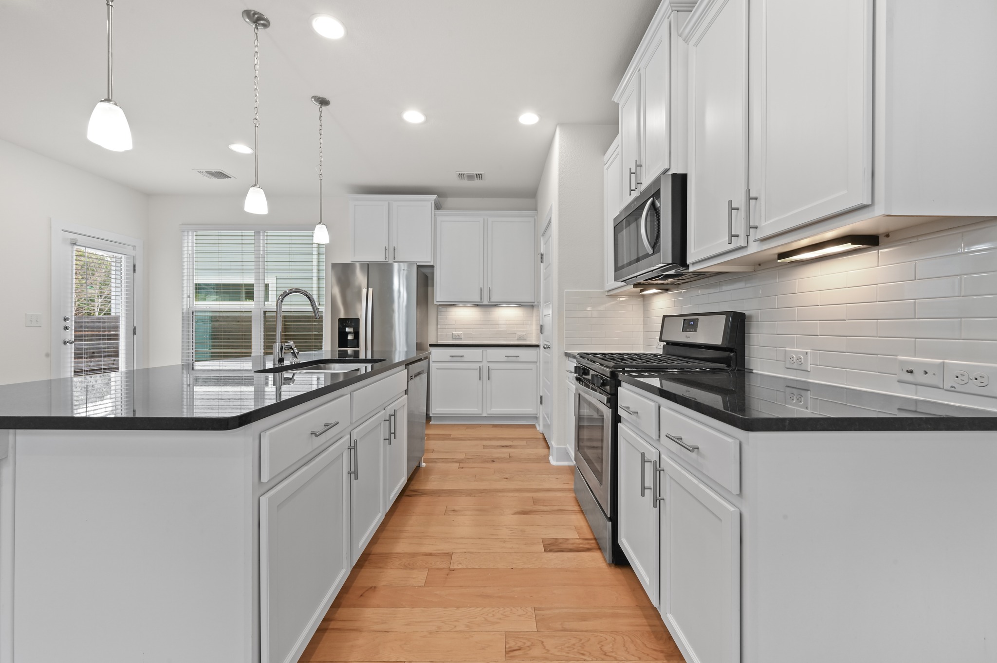2204 Theseus Pass Austin, TX 78741 - Photo 9 of 31 a large kitchen with stainless steel appliances kitchen island granite countertop a stove a sink and a refrigerator