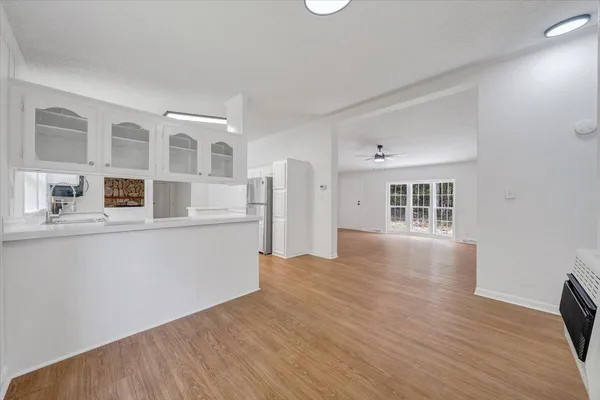 a view of empty room with wooden floor and kitchen
