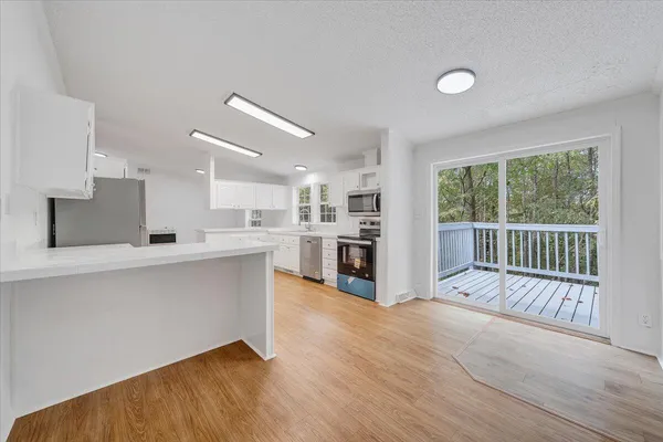 a open kitchen with white cabinets and wooden floor