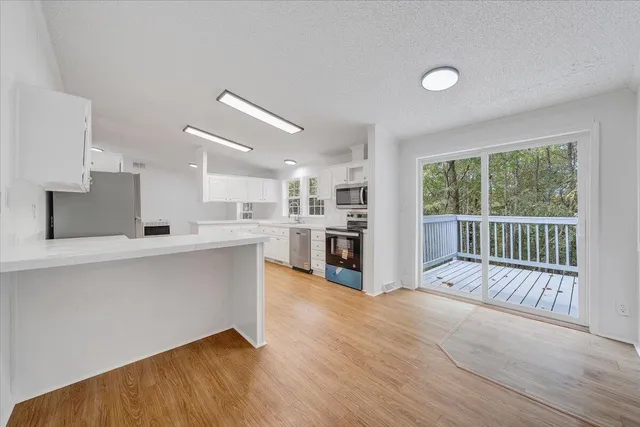 a open kitchen with white cabinets and wooden floor
