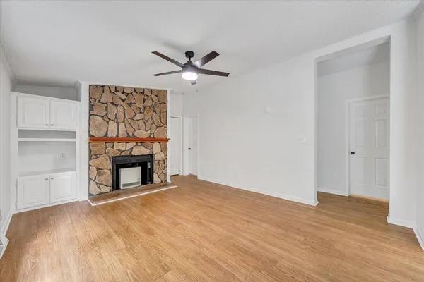 a view of an empty room with wooden floor fireplace and a window