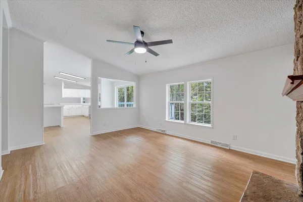 a view of an empty room with a window and wooden floor
