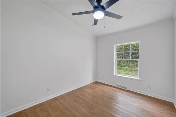 an empty room with a window and a fan