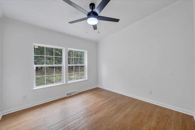 an empty room with wooden floor and windows