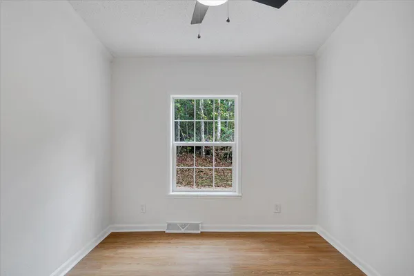 an empty room with wooden floor chandelier and window