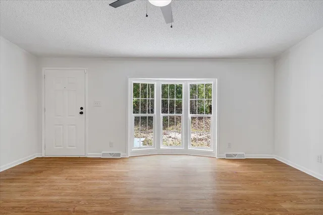 a view of an empty room with wooden floor and a window