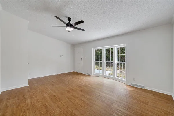 a view of an empty room with a window and wooden floor
