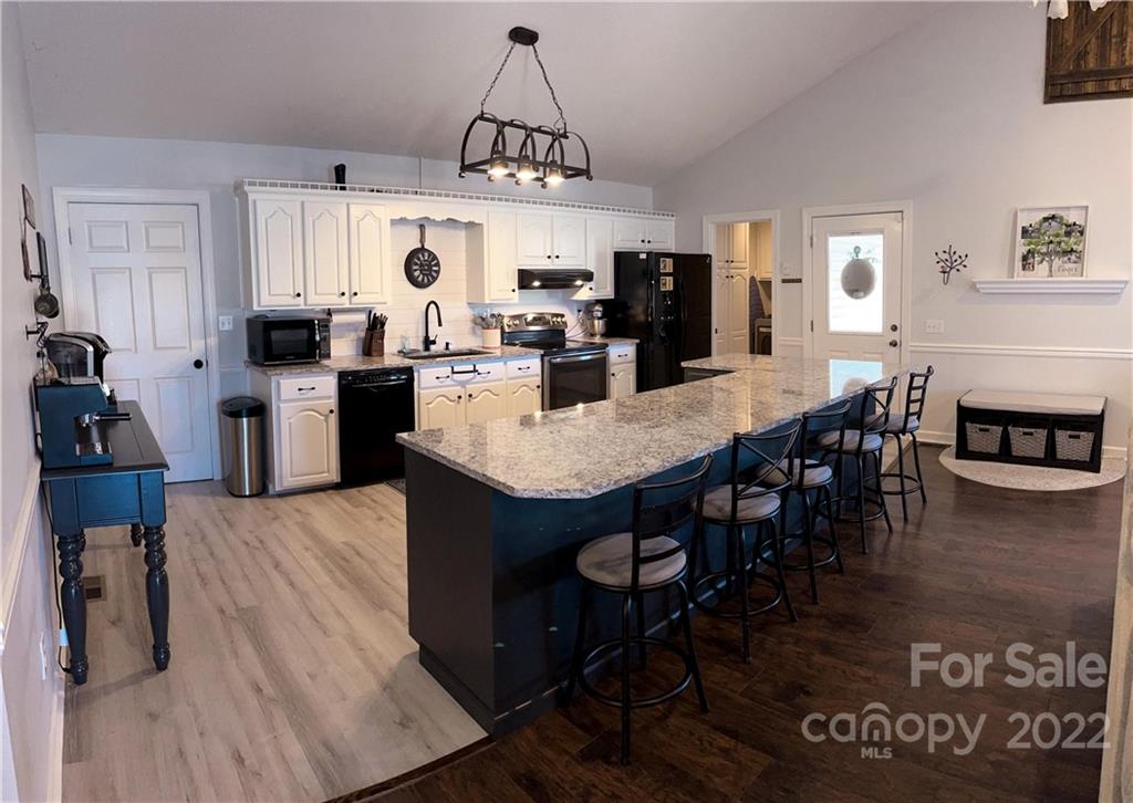 270 Tom Laney Road Lancaster, SC 29720 - Photo 9 of 28 a open kitchen with stainless steel appliances granite countertop a stove a refrigerator a kitchen island a dining table and chairs with wooden floor