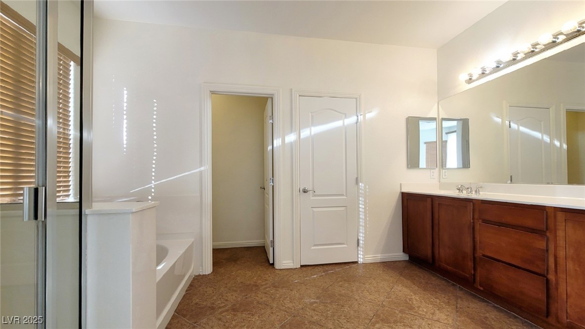 5913 Altissimo Street North Las Vegas, NV 89081 - Photo 19 of 37 Bathroom featuring vanity, a shower stall, a garden tub, and dark tile patterned flooring