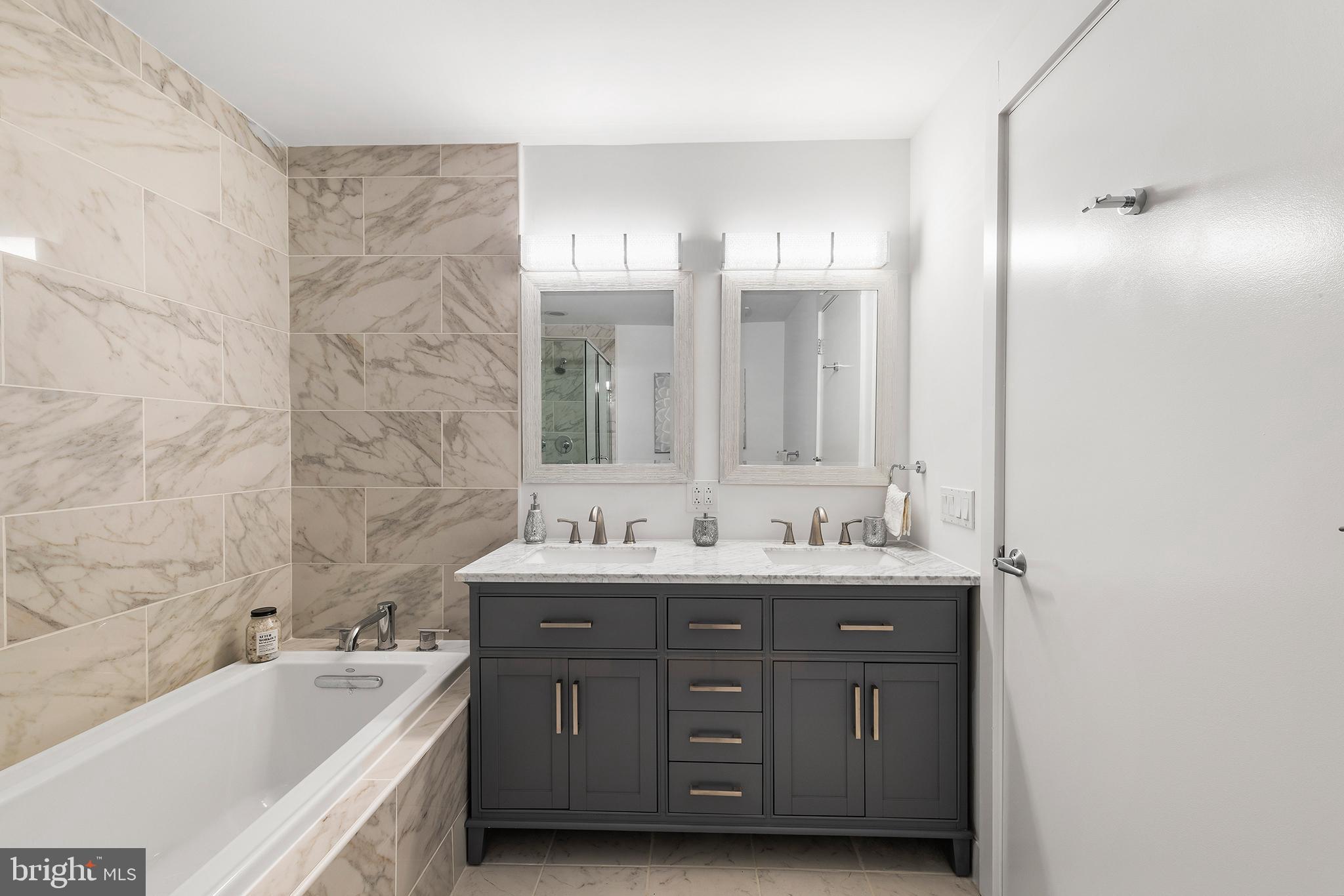 1101 Locust Street, Unit 8B Philadelphia, PA 19107 - Photo 23 of 36 a bath room with a sink double vanity granite tub shower and a mirror