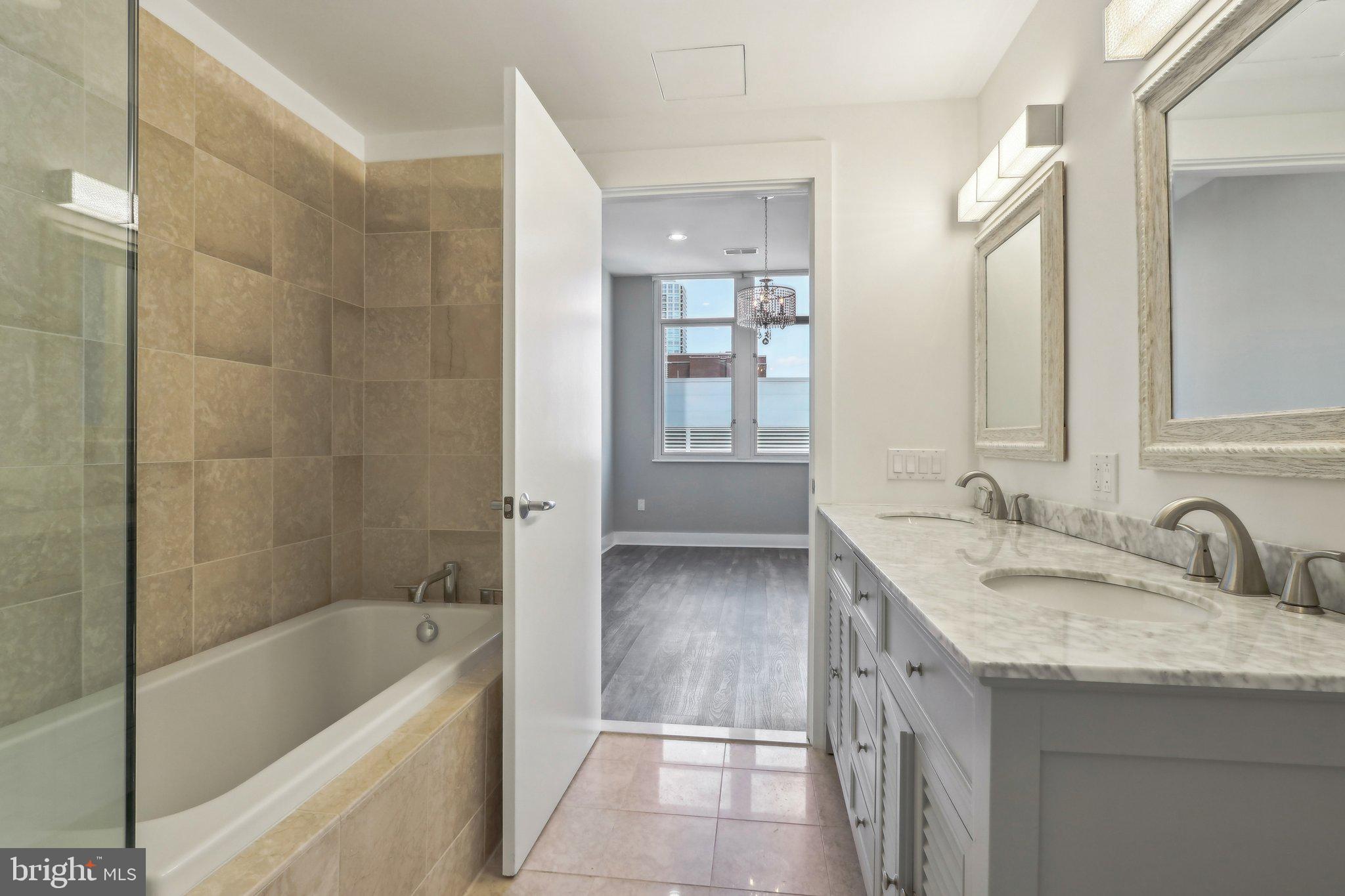 1101 Locust Street, Unit 8B Philadelphia, PA 19107 - Photo 31 of 36 a bathroom with a granite countertop tub sink and mirror
