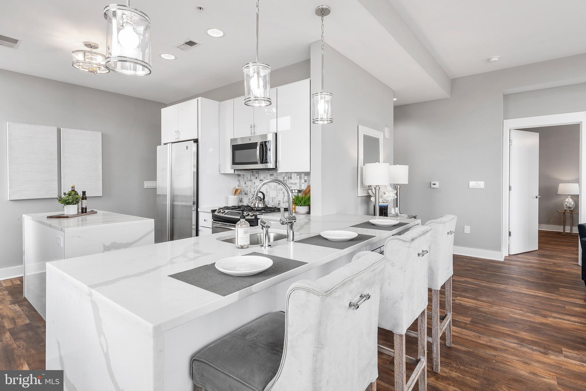 1101 Locust Street, Unit 8B Philadelphia, PA 19107 - Photo 8 of 36 a kitchen with stainless steel appliances kitchen island granite countertop a dining table and chairs