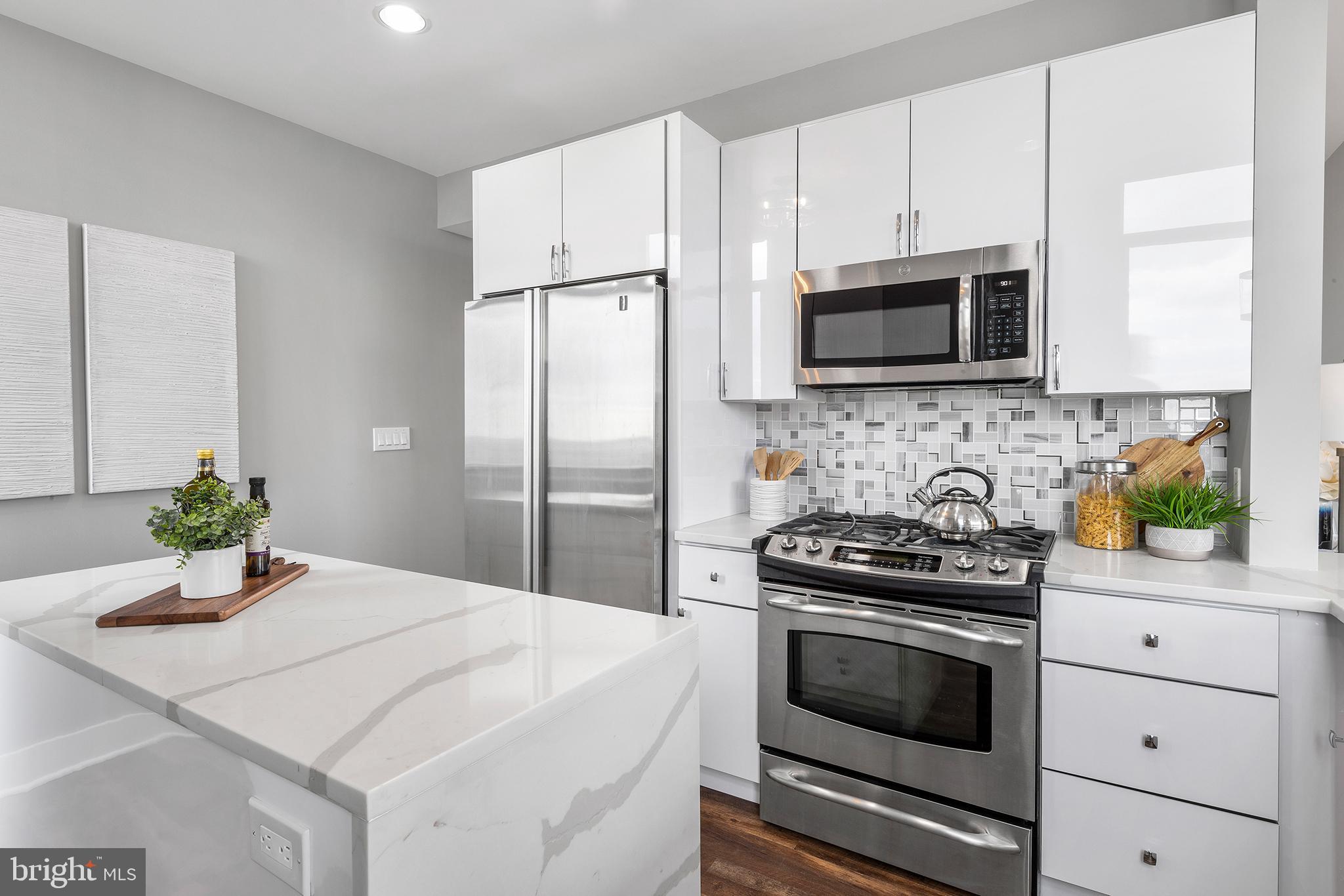 1101 Locust Street, Unit 8B Philadelphia, PA 19107 - Photo 9 of 36 a kitchen with granite countertop white cabinets and stainless steel appliances