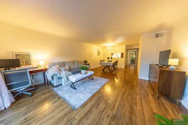 a living room with couches and a flat screen tv with kitchen view