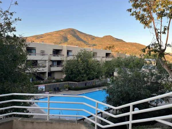 a view of a white house with a mountain yard and large trees