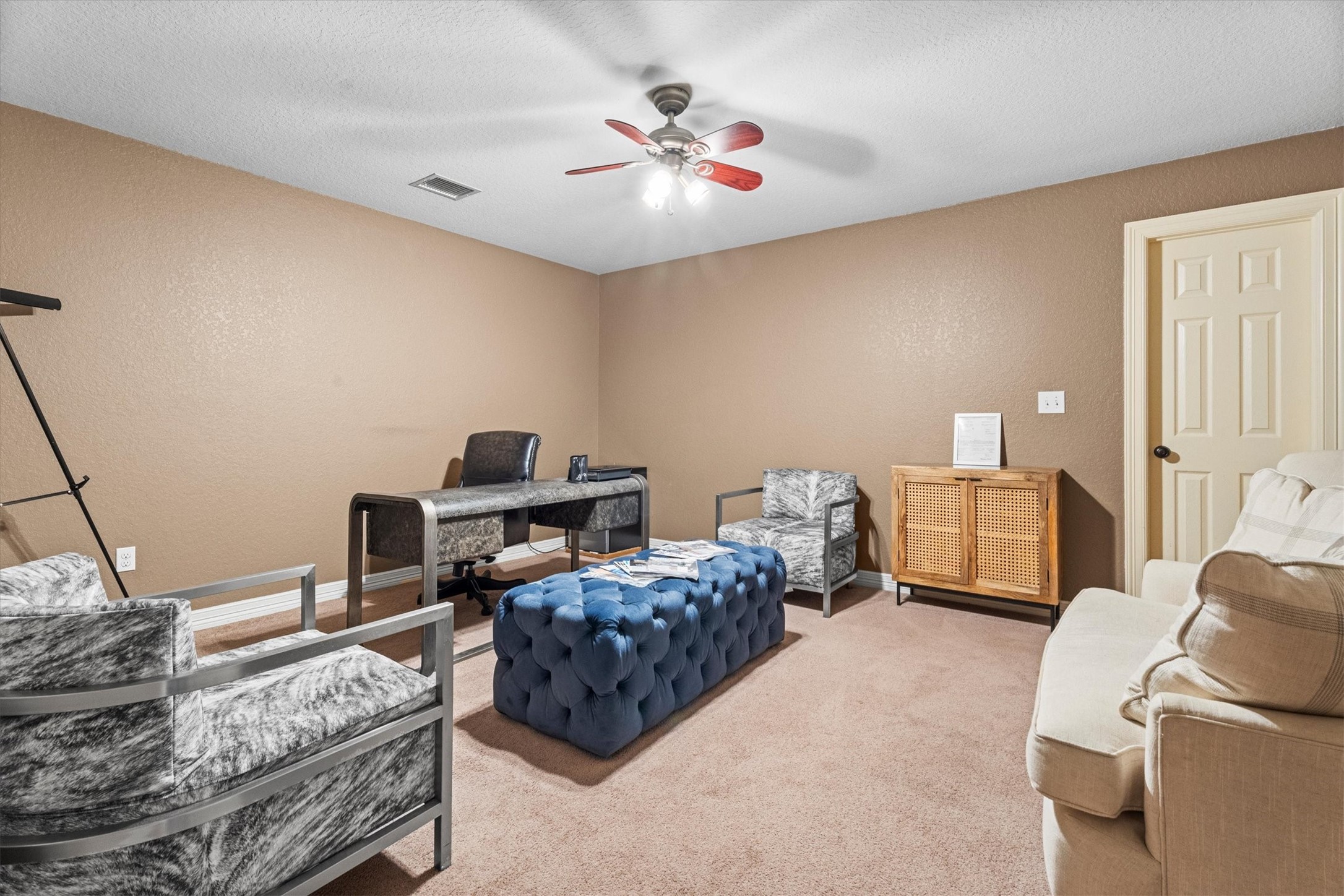 11066 Sh 242 Conroe, TX 77385 - Photo 17 of 21 This room serves as a cozy office or den, featuring a modern desk, comfortable seating, and a ceiling fan. The walls are painted a warm beige, and the space is carpeted, providing a soft, inviting atmosphere.