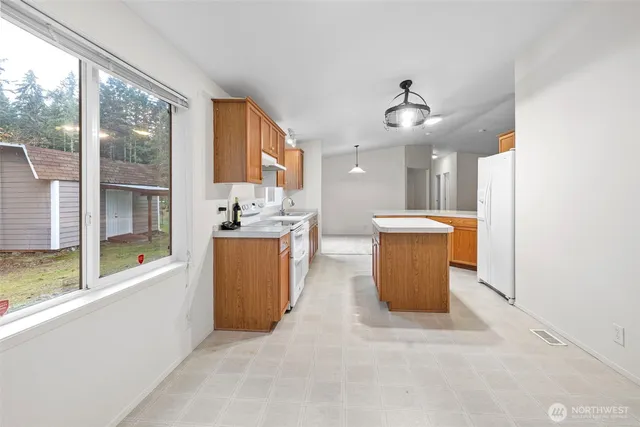 a view of a kitchen with kitchen island a sink a counter top space and stainless steel appliances