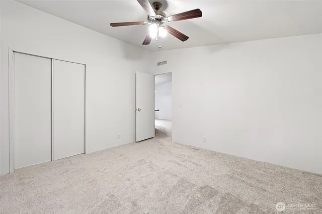 an empty room with closet and a chandelier fan
