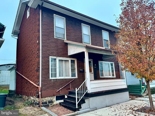 a front view of a house with a tree