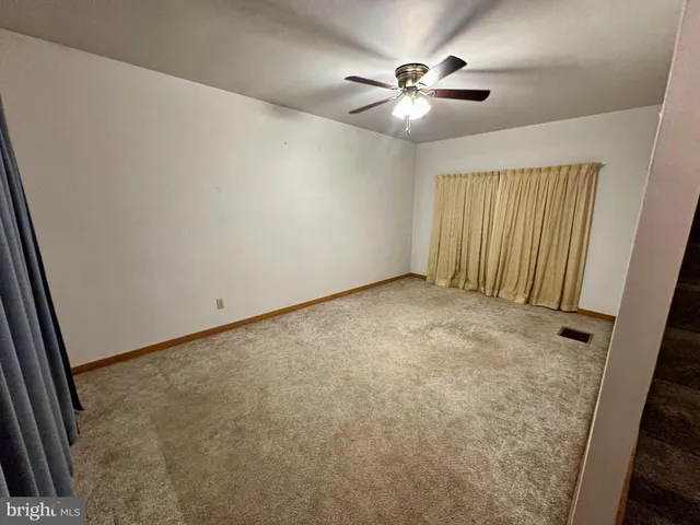 an empty room with chandelier fan and windows