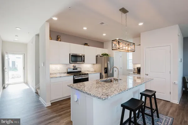 a kitchen with stainless steel appliances granite countertop a stove top oven a refrigerator a sink and a dining table with wooden floor